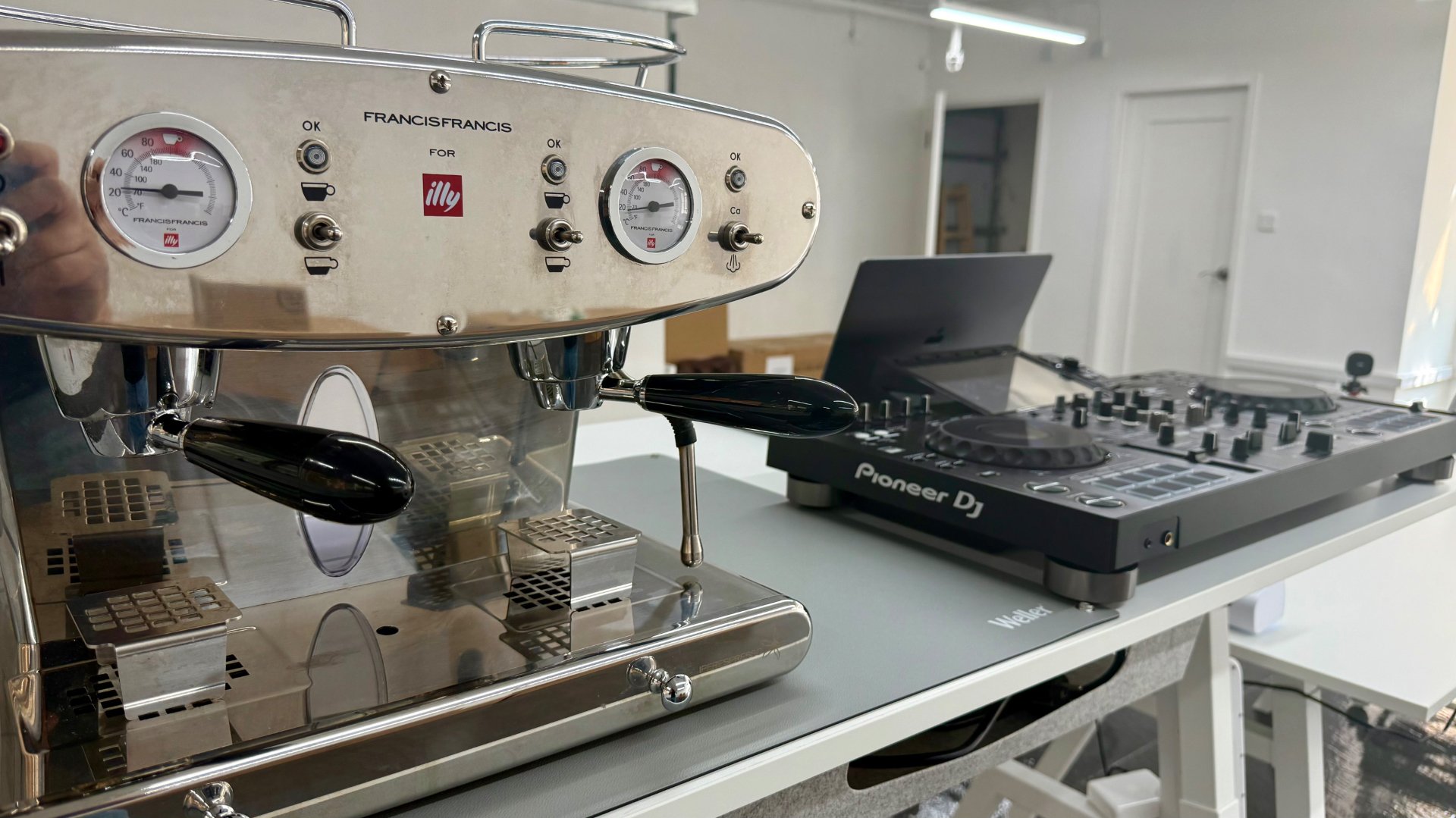 Close-up of the espresso machine with the DJ console on the lab bench behind it